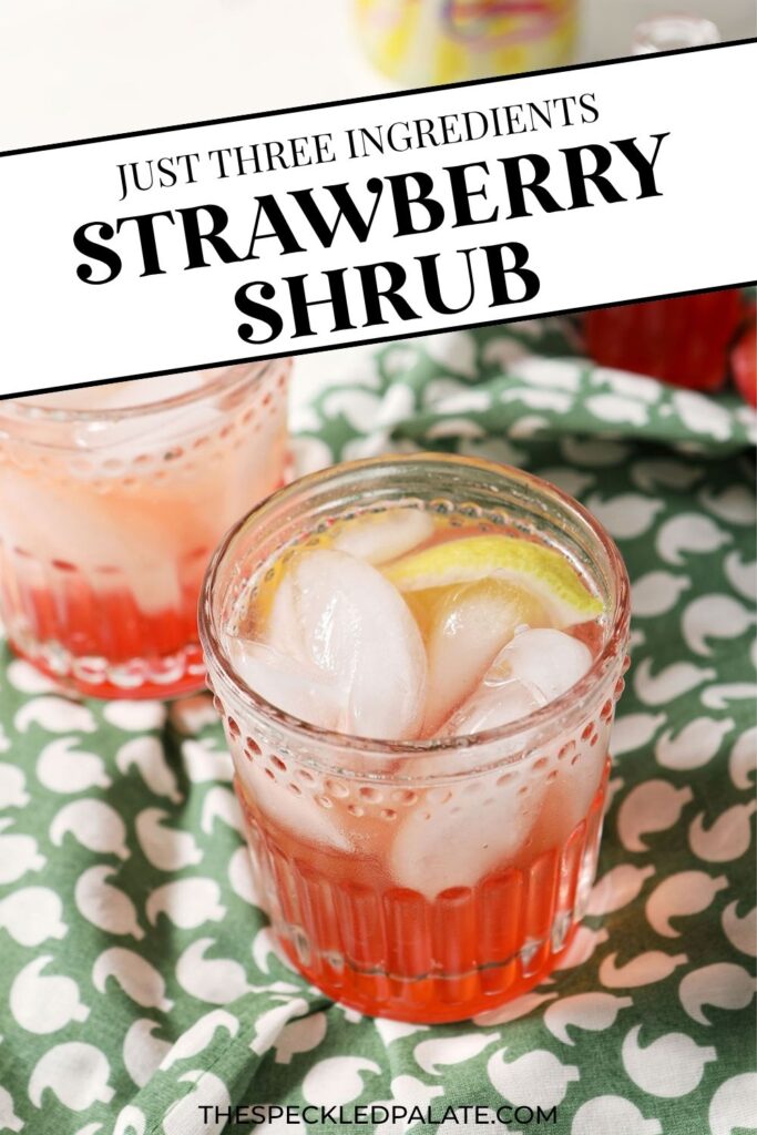 Two glasses of strawberry shrub, garnished with lemon wedges, on a green patterned linen, with the text just three ingredients strawberry shrub