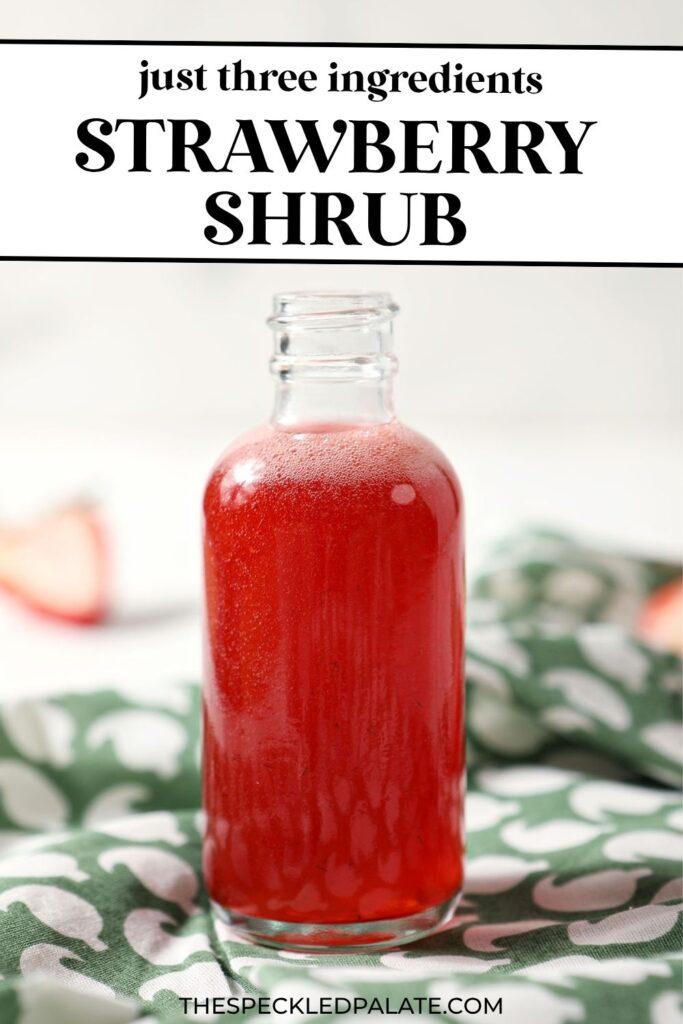 A bottle of homemade strawberry shrub syrup on a green patterned linen with the text just three ingredients strawberry shrub