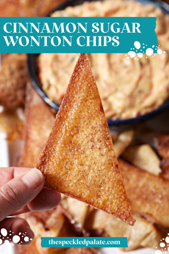 A hand holds a triangular Cinnamon Sugar Wonton Chip about a platter of more chips and carrot cake dip with the text cinnamon sugar wonton chips