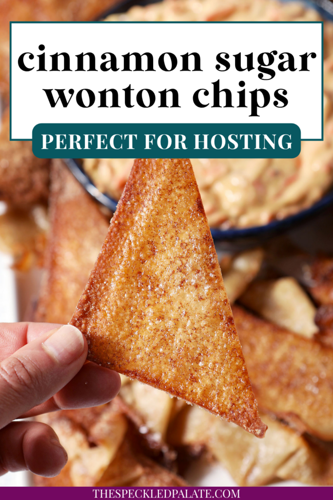 A hand holds a triangular Cinnamon Sugar Wonton Chip about a platter of more chips and carrot cake dip with the text cinnamon sugar wonton chips perfect for hosting