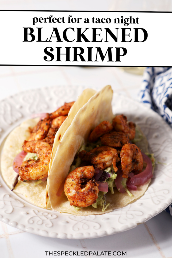 Two blackened shrimp tacos on a white plate on a white tiled surface