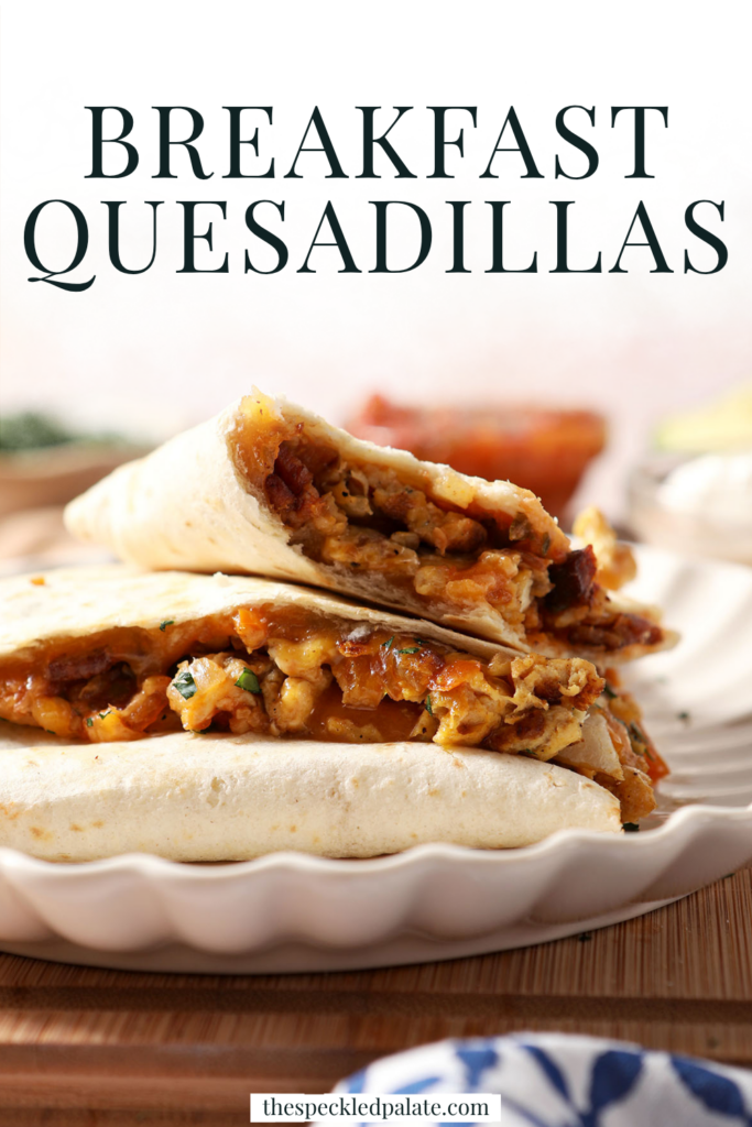 Breakfast quesadillas stacked on a plate on top of a wooden cutting board next to bowls of salsa and sour cream and an avocado. With the Text "Breakfast Quesadillas" written across the top.