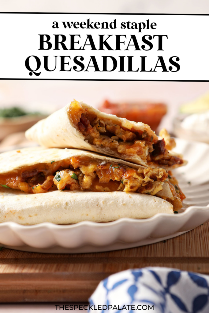 Breakfast quesadillas stacked on a plate on top of a wooden cutting board next to bowls of salsa and sour cream and an avocado. With the Text "Breakfast Quesadillas. Perfect for Hosting." written across the top.