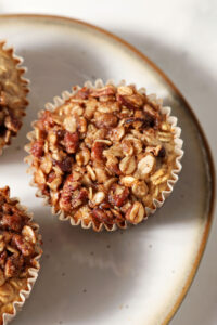 Closeup of a baked oatmeal cup on a plate from above with two more