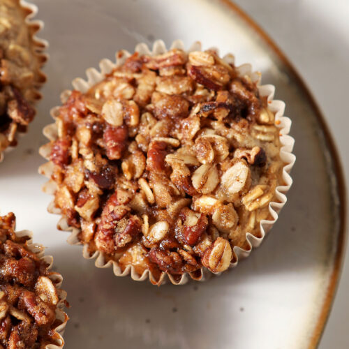 Closeup of a baked oatmeal cup on a plate from above with two more