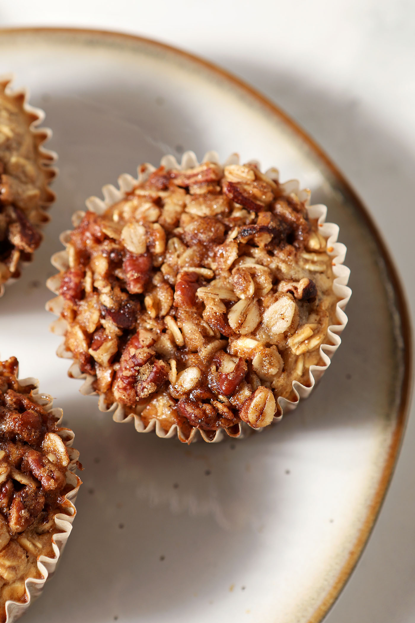 Closeup of a baked oatmeal cup on a plate from above with two more