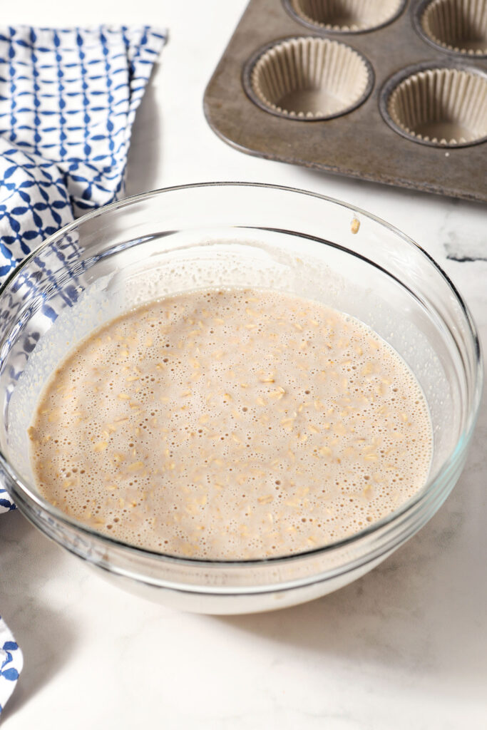 Oatmeal cup mixture in a bowl next to an empty muffin tin