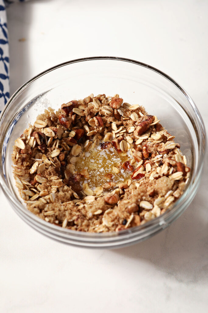 Brown sugar, salt, pecans and oats in a bowl with melted butter, before mixing