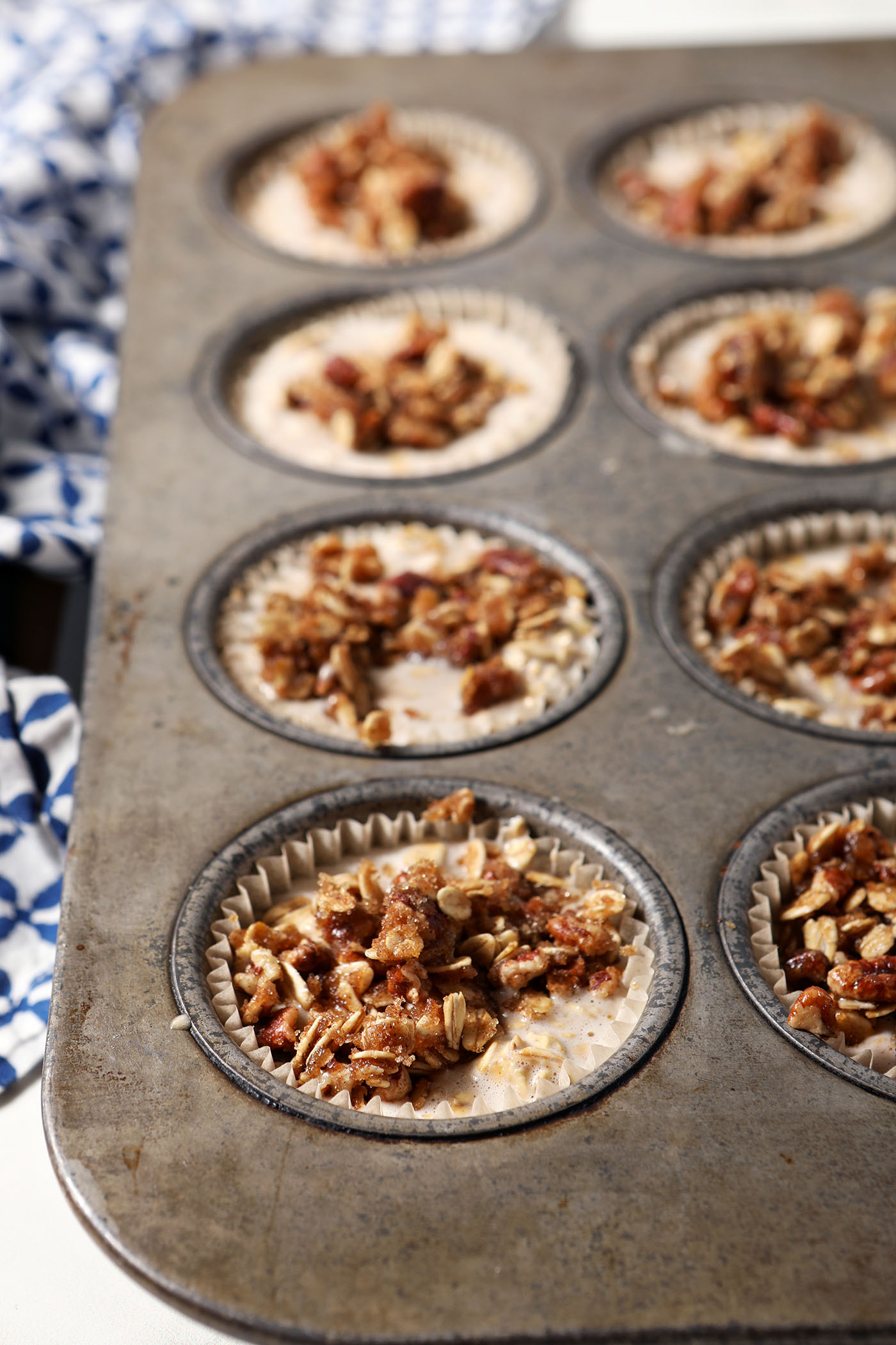 Oatmeal cup mixture with a streusel topping in a muffin tin before baking