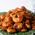 Blackened shrimp piled high on a green plate