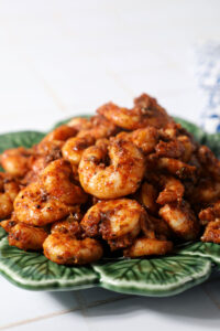 Blackened shrimp piled high on a green plate