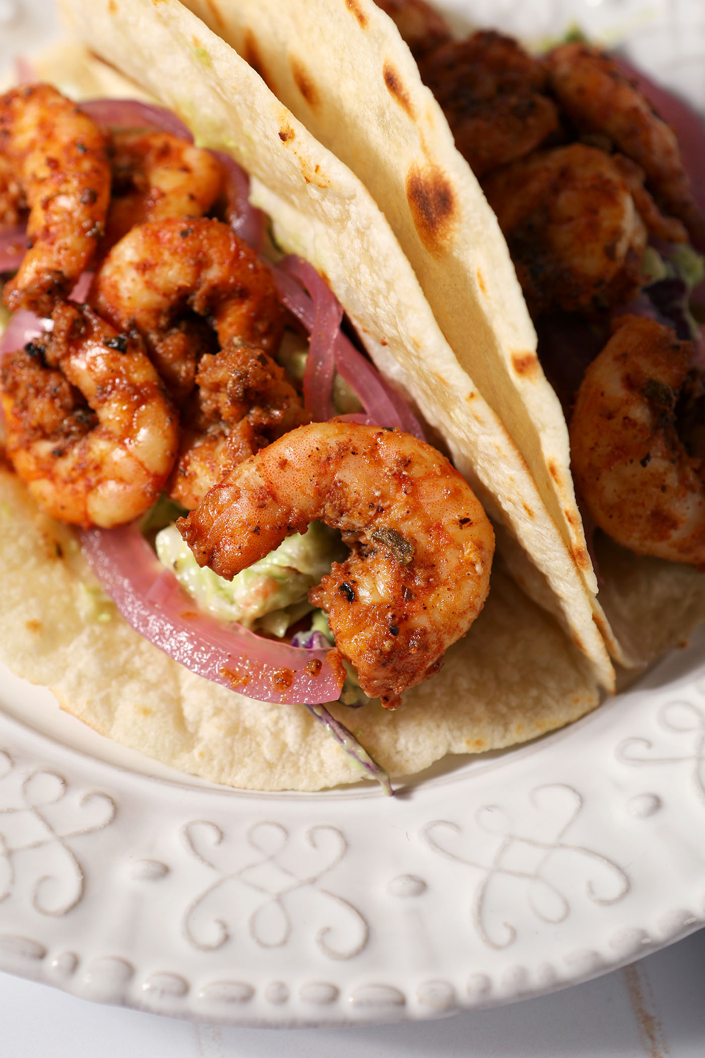 Closeup of blackened shrimp on a taco on a white plate