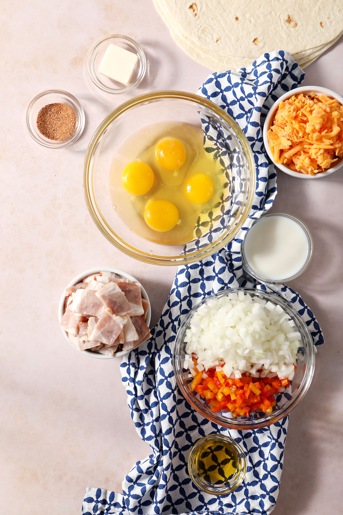 Ingredients to make breakfast quesadillas in bowls on a light brown marble surface