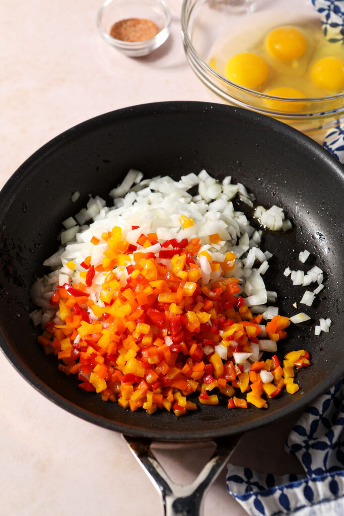 Diced peppers and onion in a skillet before cooking