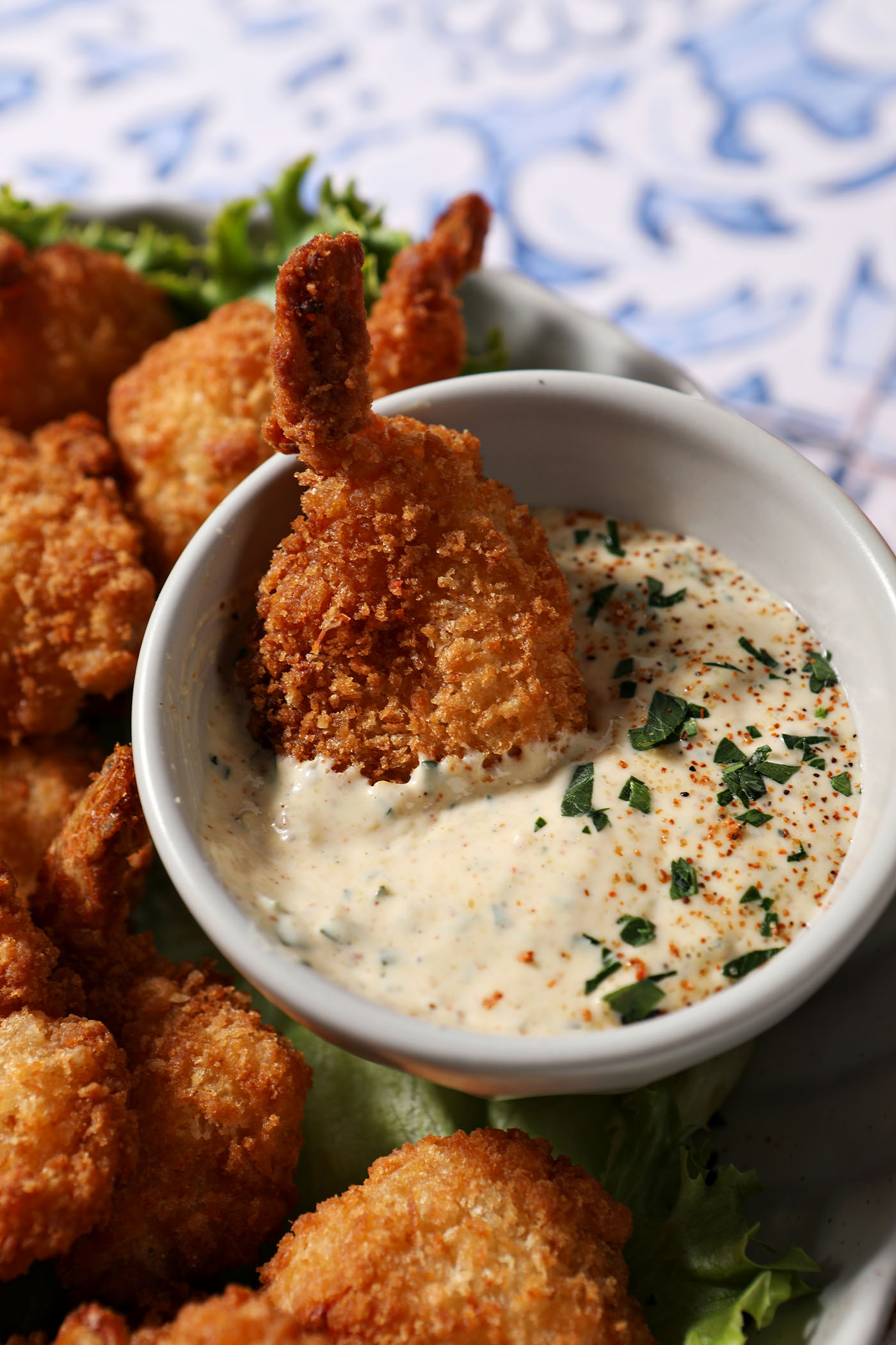 a plate of fried shrimp surrounding the cajun remoulade sauce cup with a shrimp dipped into the cajun remoulade sauce.