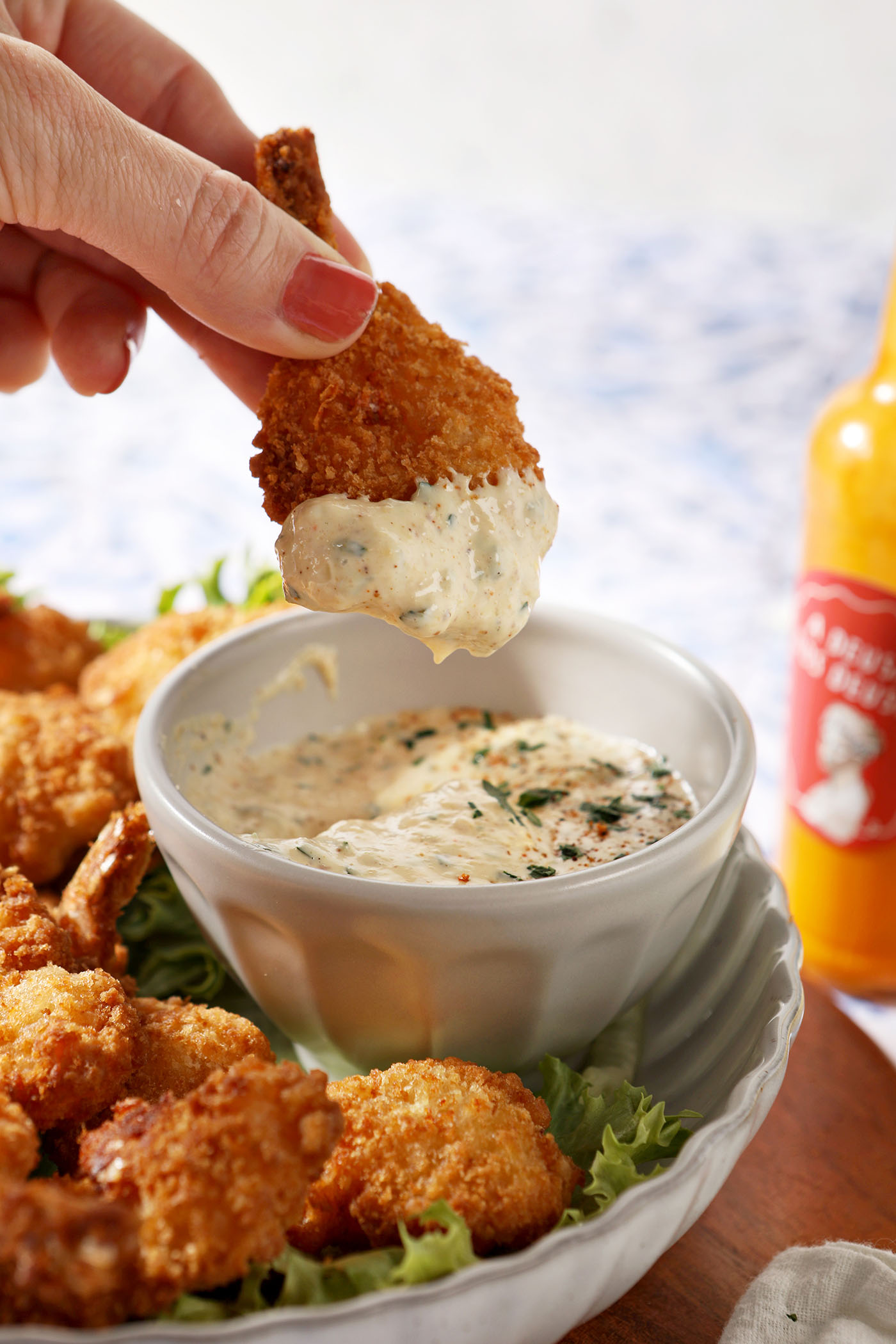 A fried shrimp freshly dipped in our cajun remoulade surrounded by a plate of fried shrimp.