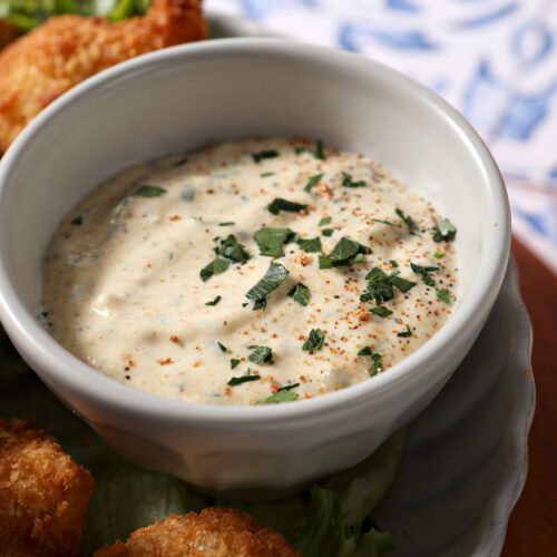 Close up picture of cajun remoulade in a ceramic cup alongside fried shrimp