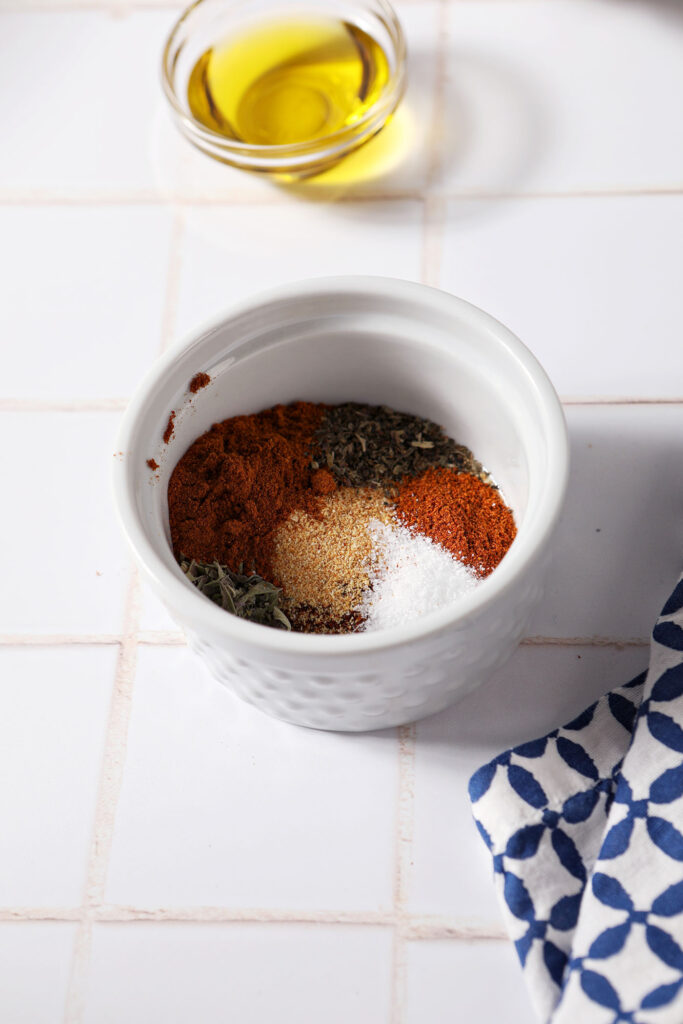 A bowl of seasoning before mixing on a white tiled surface
