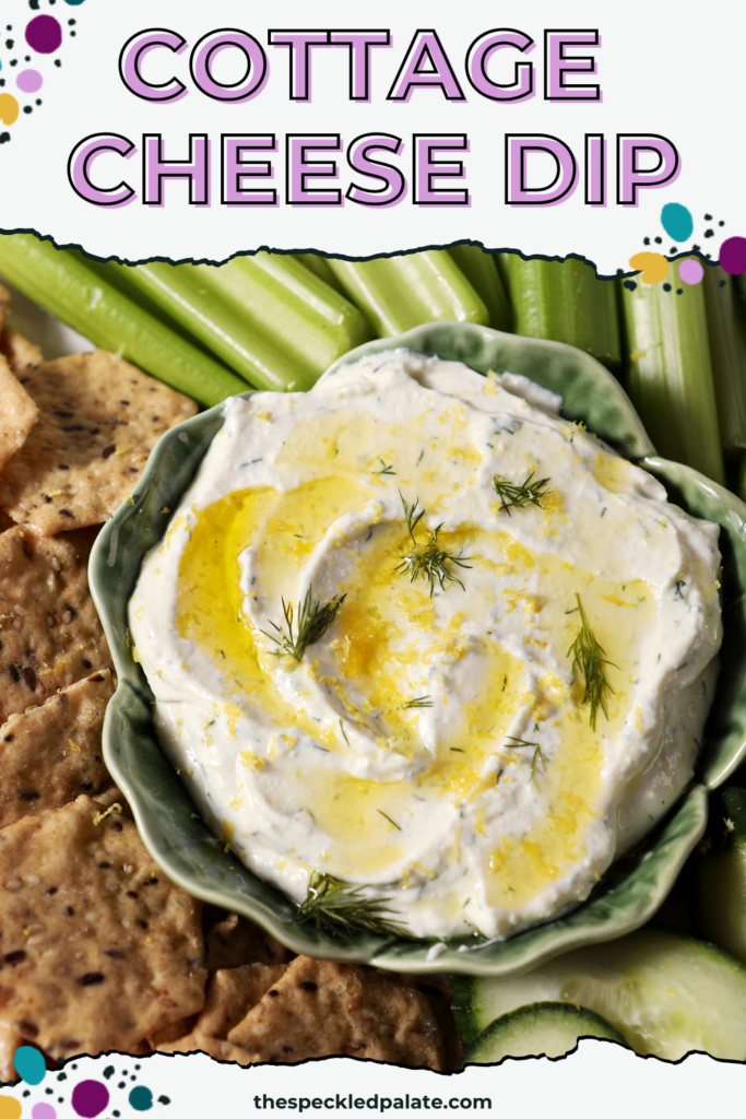 Overhead of a savory creamy dip, garnished with dill, olive oil and lemon zest, on a platter with crackers, cucumber rounds and celery sticks with the text cottage cheese dip