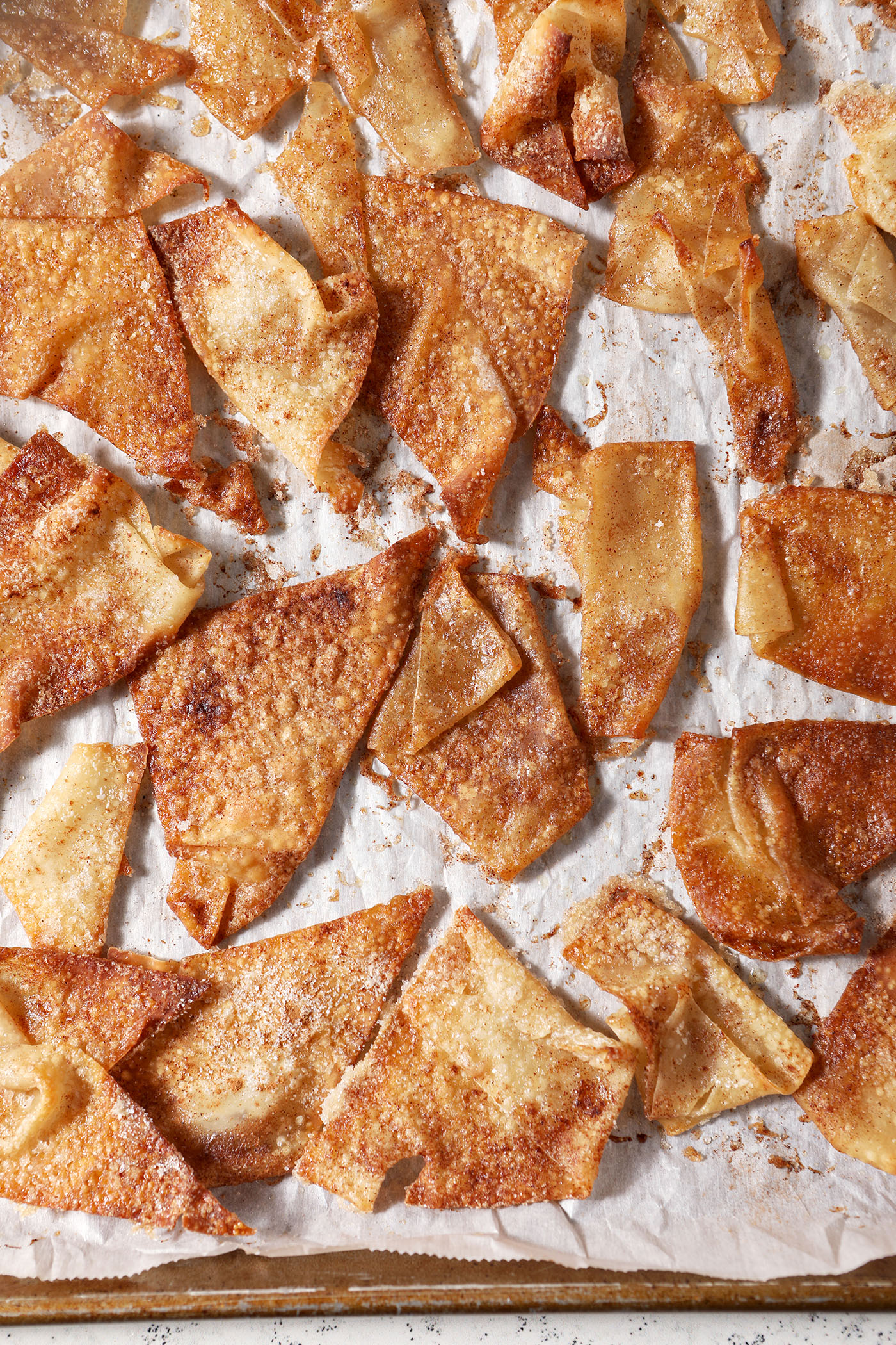 Crinkled cinnamon sugar wonton chips on a sheet pan after baking