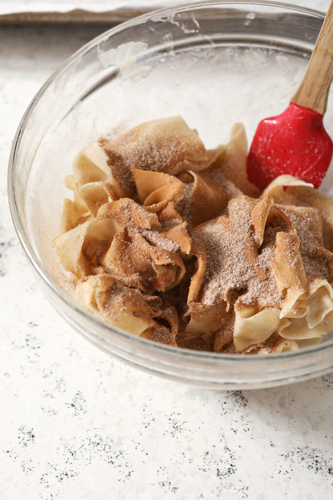 Wontons sprinkled with cinnamon sugar and butter in a bowl before mixing