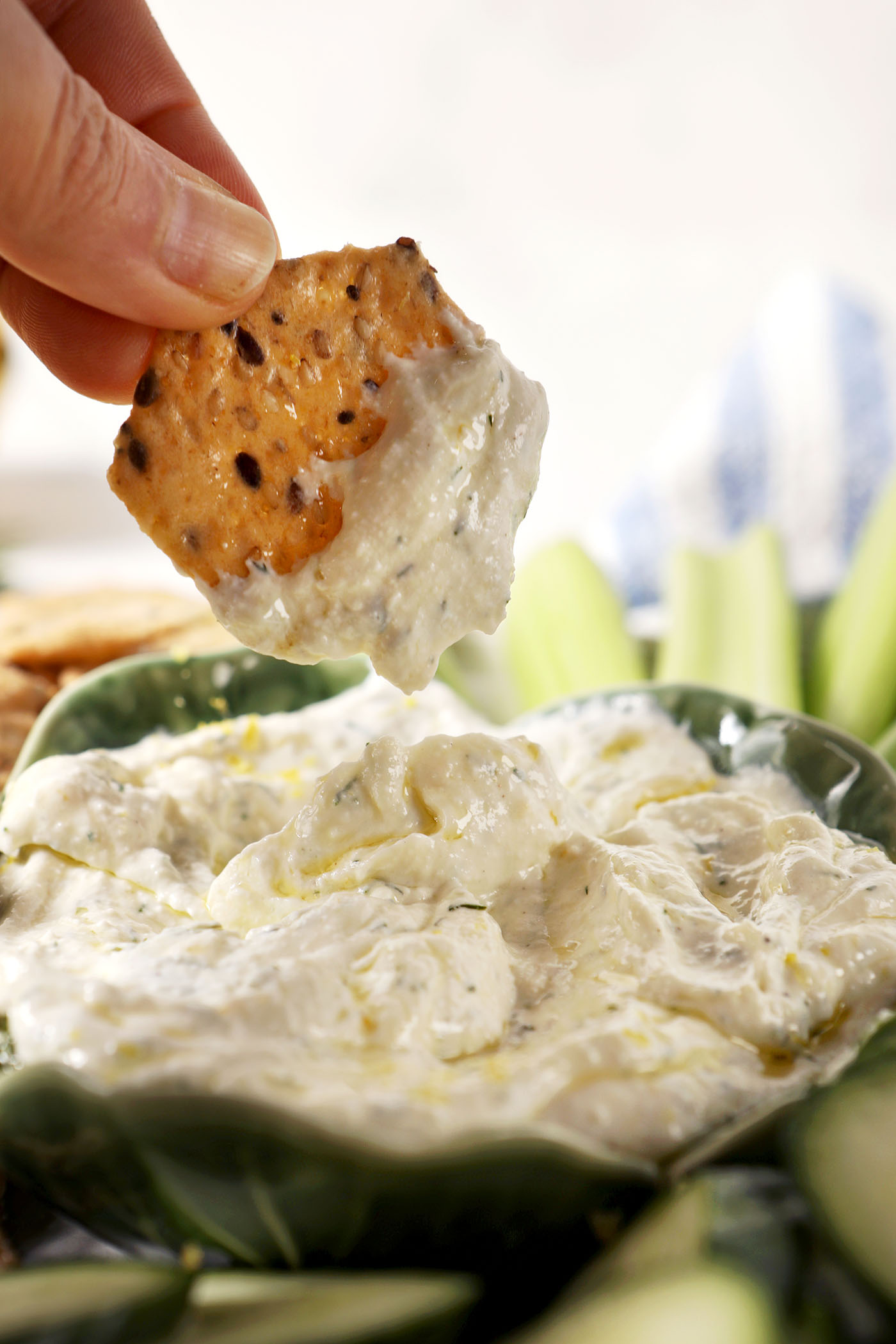 A cracker dips into a bowl of cottage cheese dip