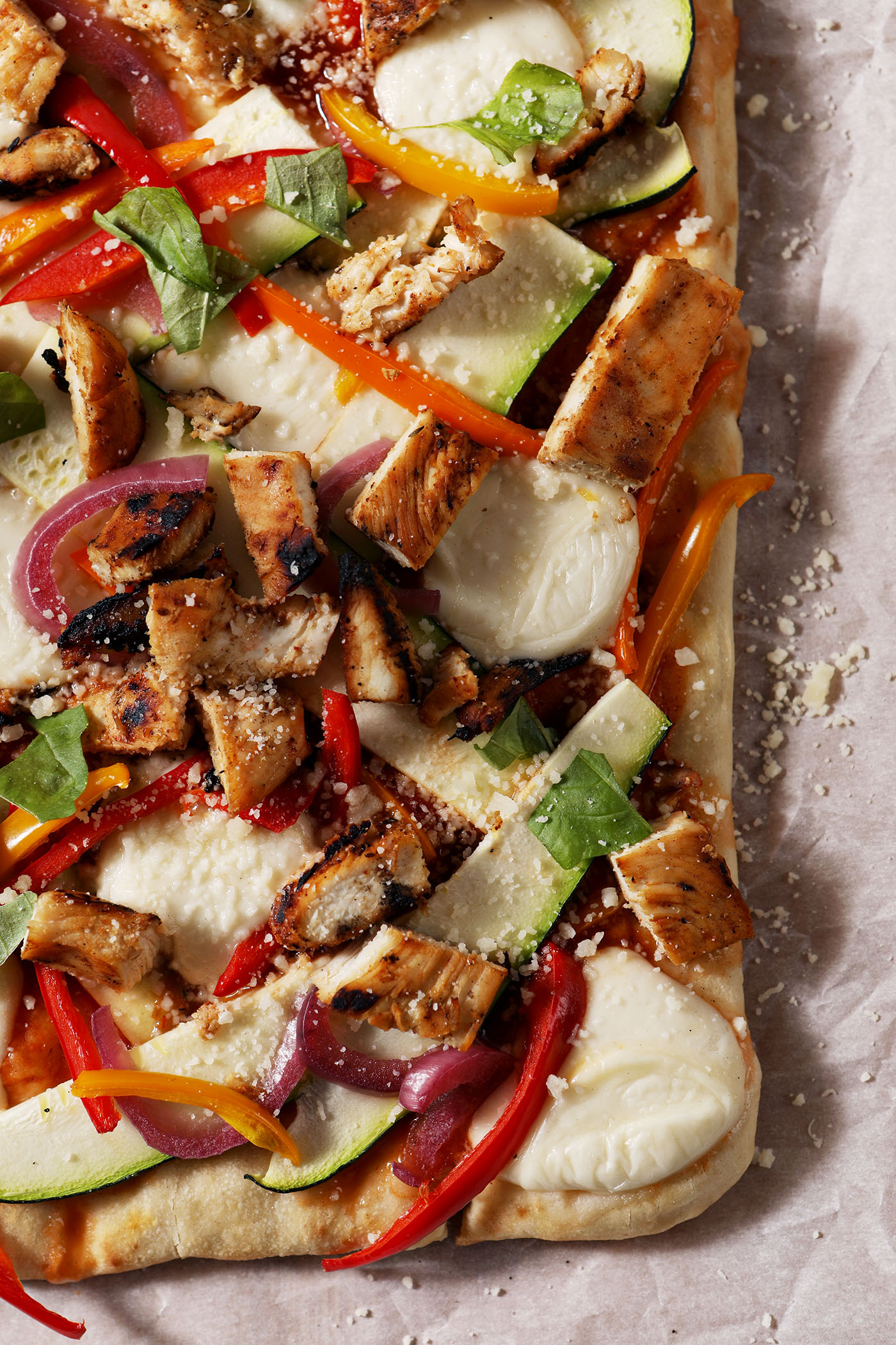Close-up of grilled barbecue chicken flatbread on a sheet of parchment paper