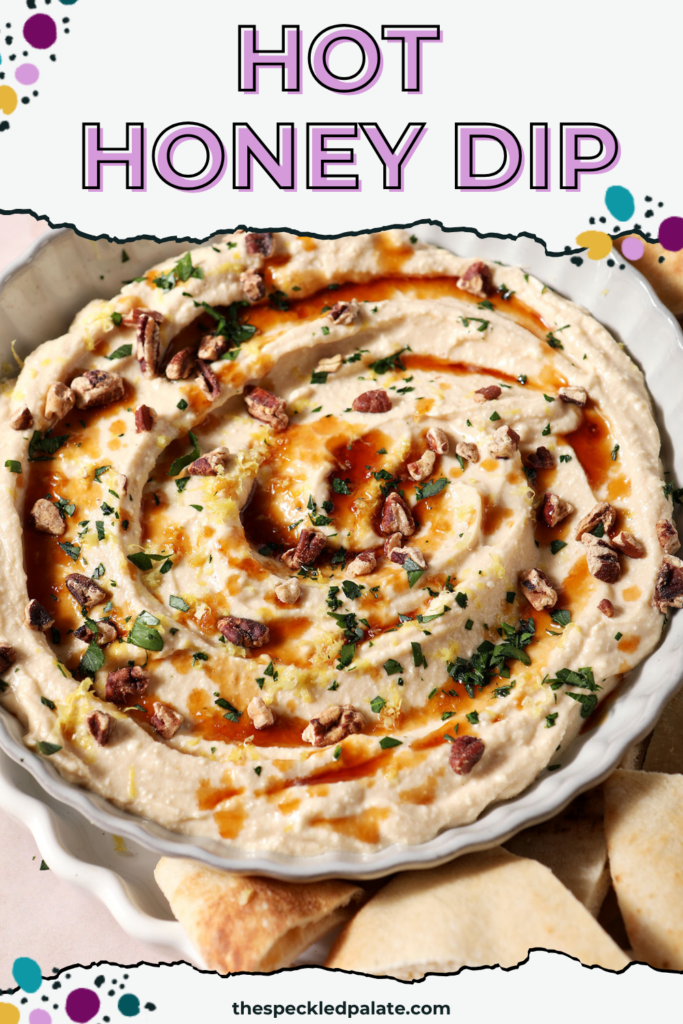 Hot honey dip, garnished with more hot honey, chopped pecans, chopped herbs and lemon zest, in a gray bowl with fresh pita