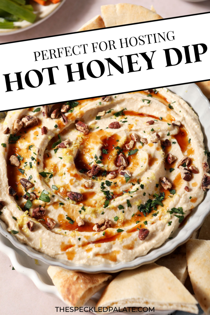Hot honey dip, garnished with more hot honey, chopped pecans, chopped herbs and lemon zest, in a gray bowl with fresh pita