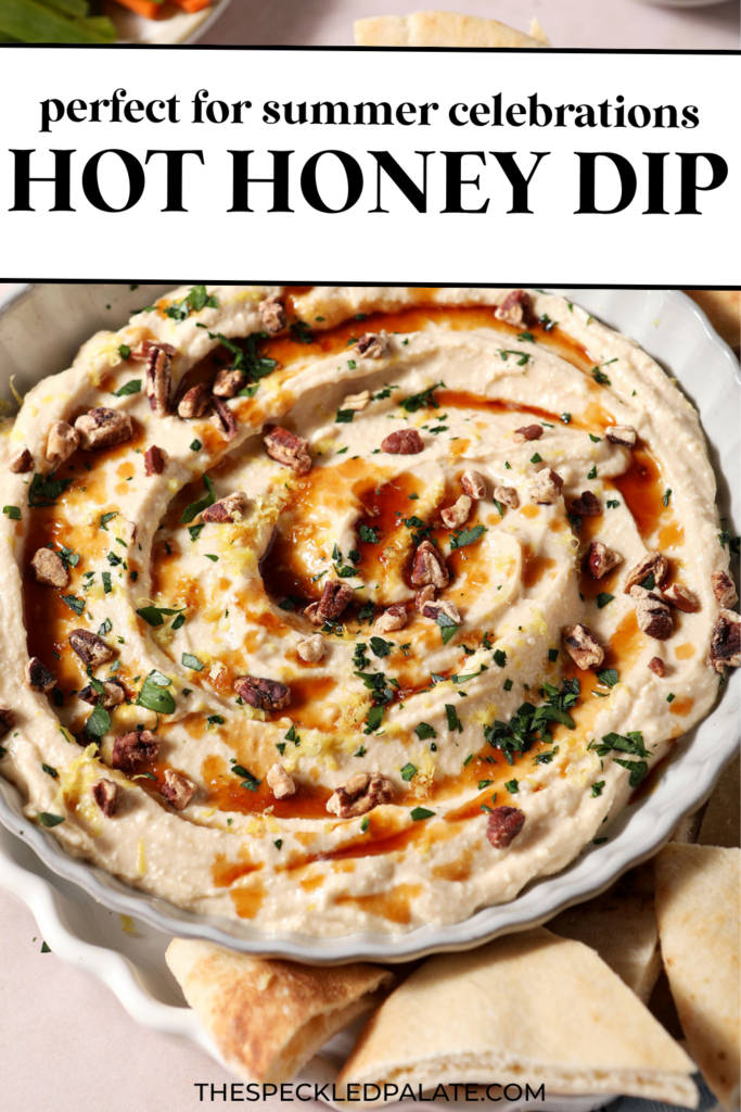 Hot honey dip, garnished with more hot honey, chopped pecans, chopped herbs and lemon zest, in a gray bowl with fresh pita