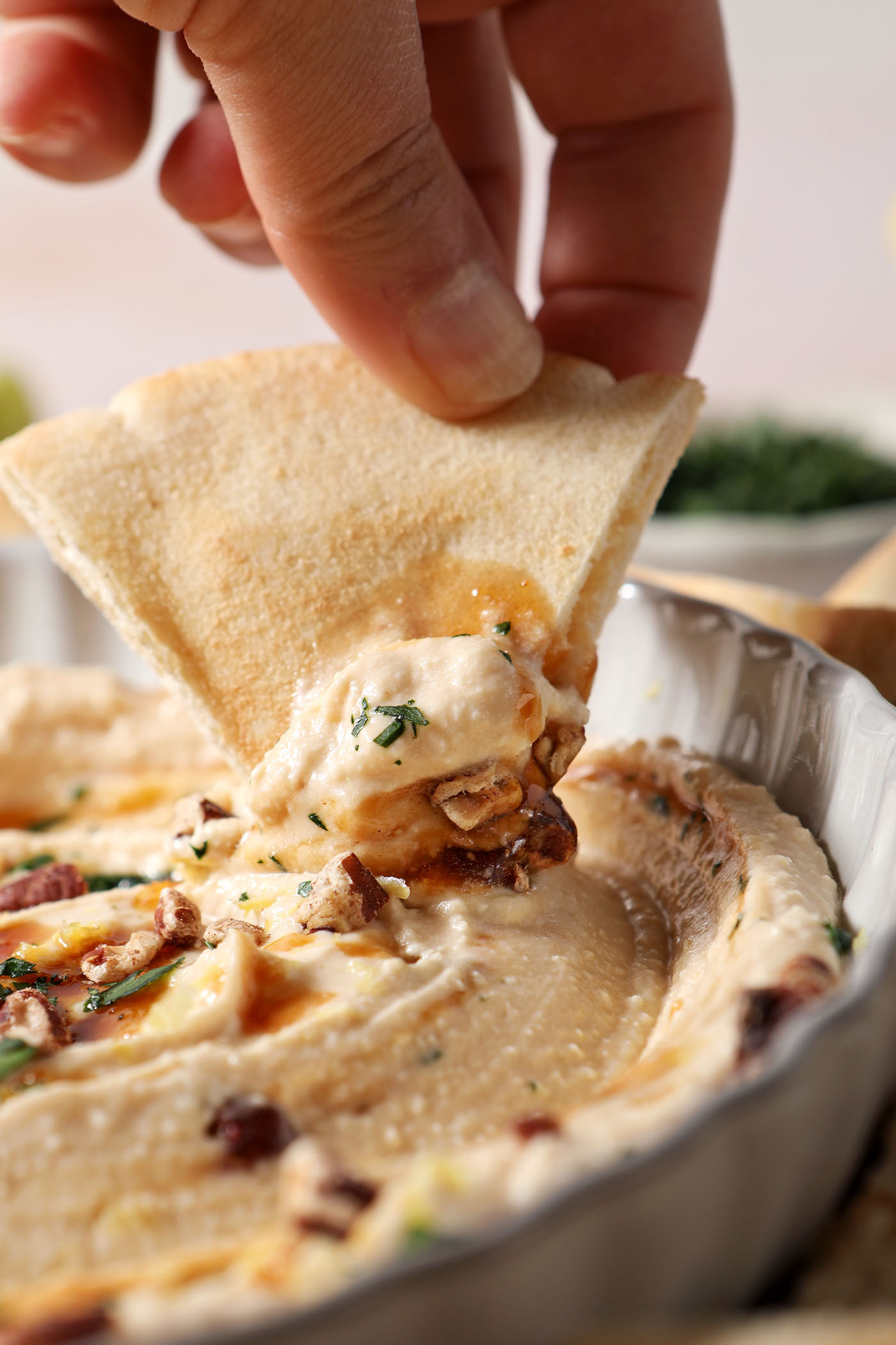 Close-up of a pita triangle scooping hot honey dip out of a bowl.