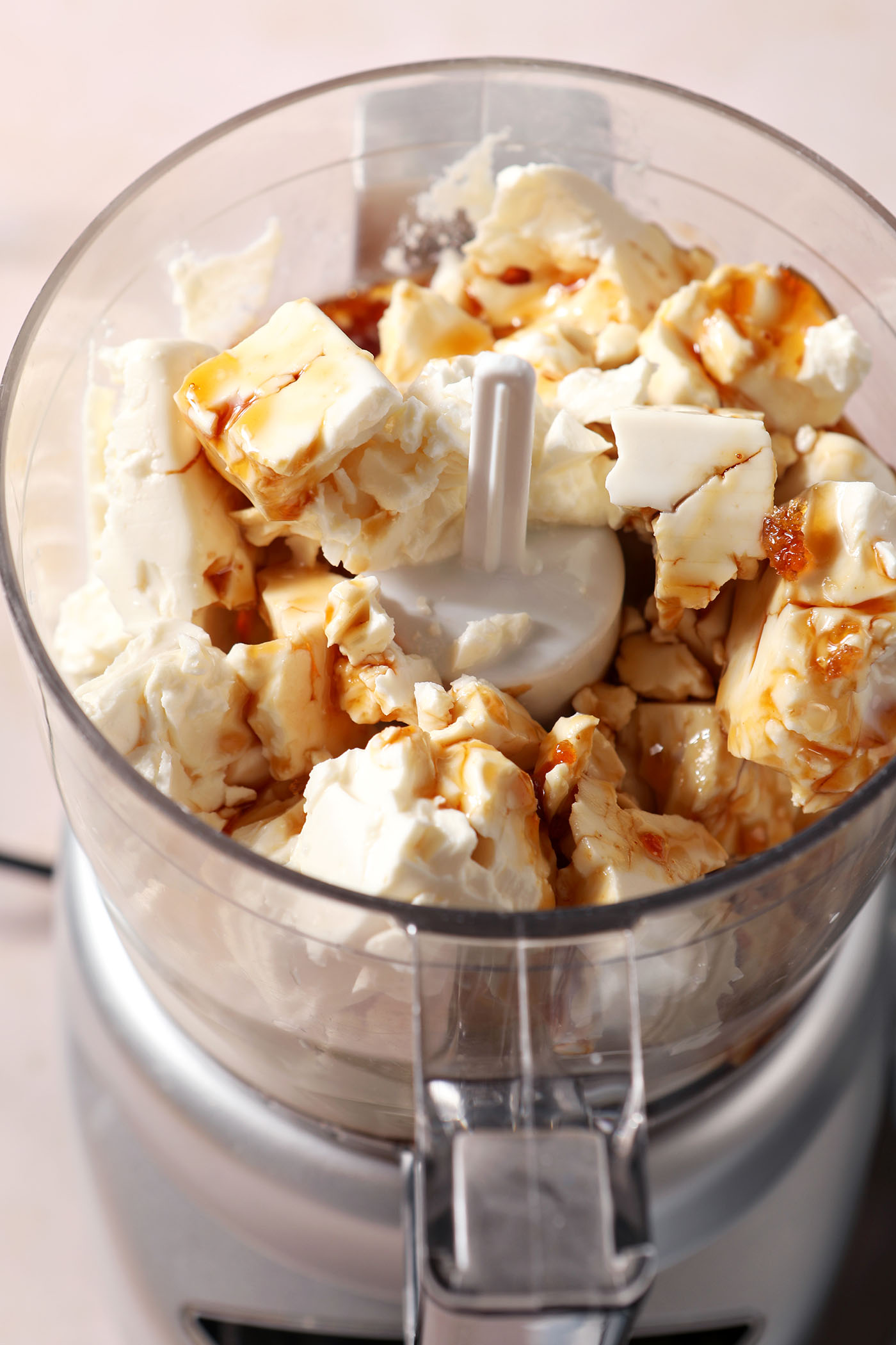 Chunks of feta with hot honey, ricotta and more ingredients in the base of a food processor