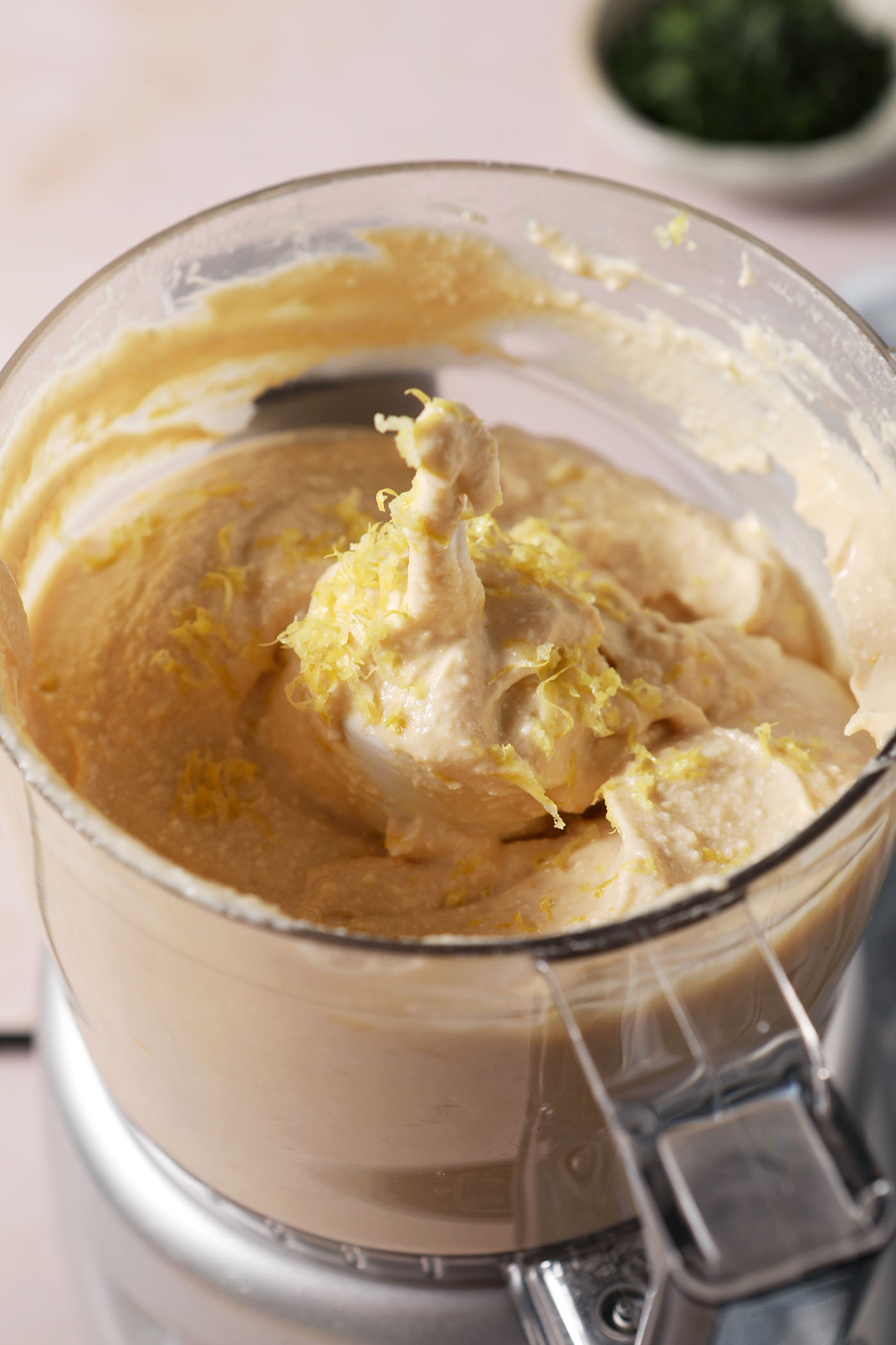 Lemon zest on top of a whipped feta dip in a food processor