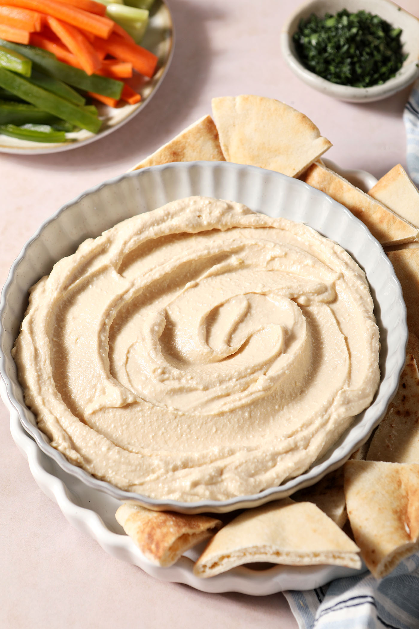 Hot honey dip in a gray bowl, surrounded by pita triangles and fresh vegetables, before garnishing