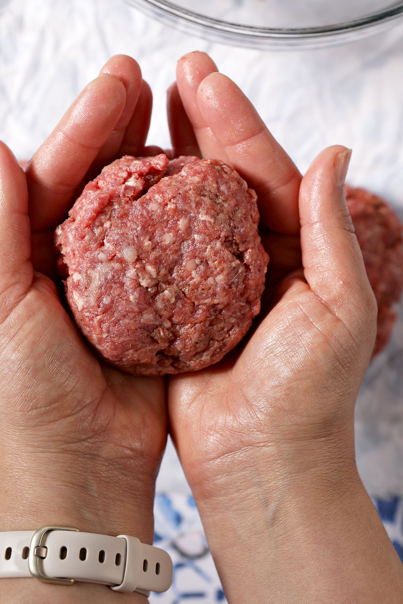 Two hands form a burger patty.