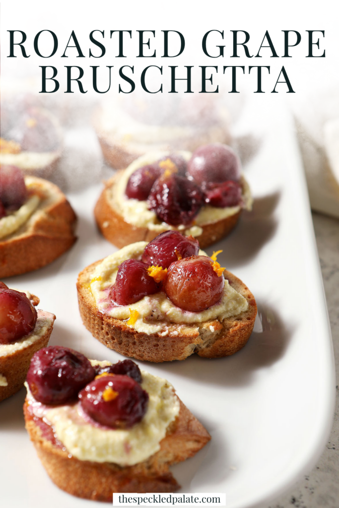 Side angle of Roasted Grape Bruschetta with Whipped Feta on a white platter