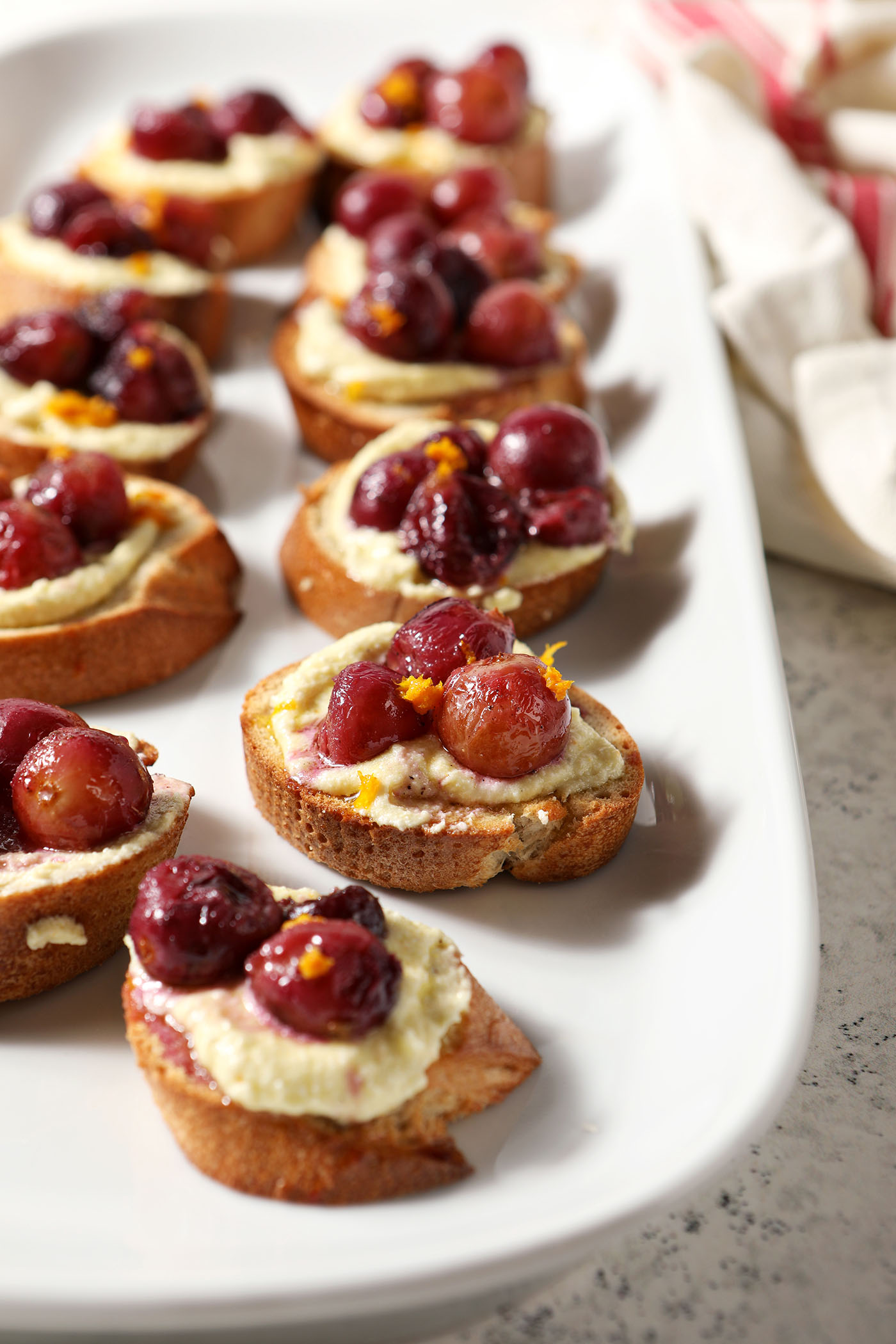 Side angle of Roasted Grape Bruschetta with Whipped Feta on a white platter