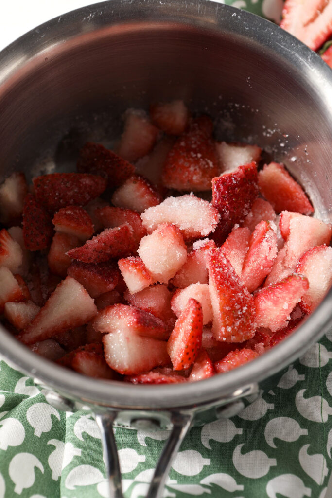 A saucepan with sliced strawberries and sugar