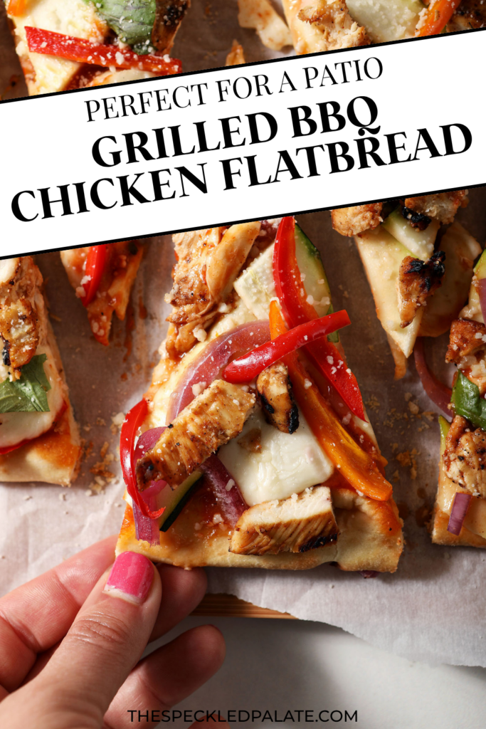 a hand grabbing a slice of grilled bbq chicken and summer veggie flatbread on a wooden serving platter with the text "Grilled BBQ Chicken Flatbread"