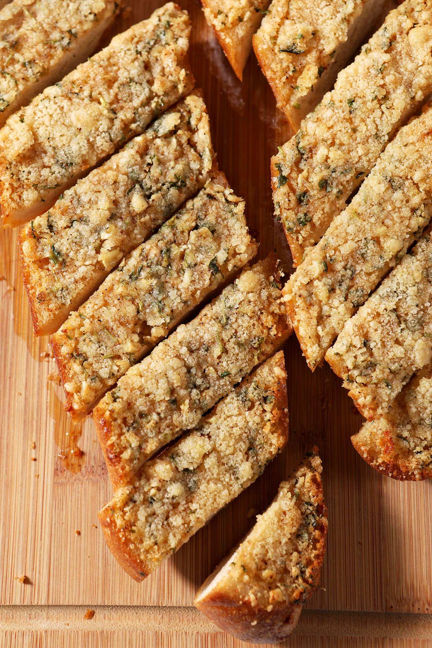 Overhead of sliced cheesy garlic bread on a wooden cutting board