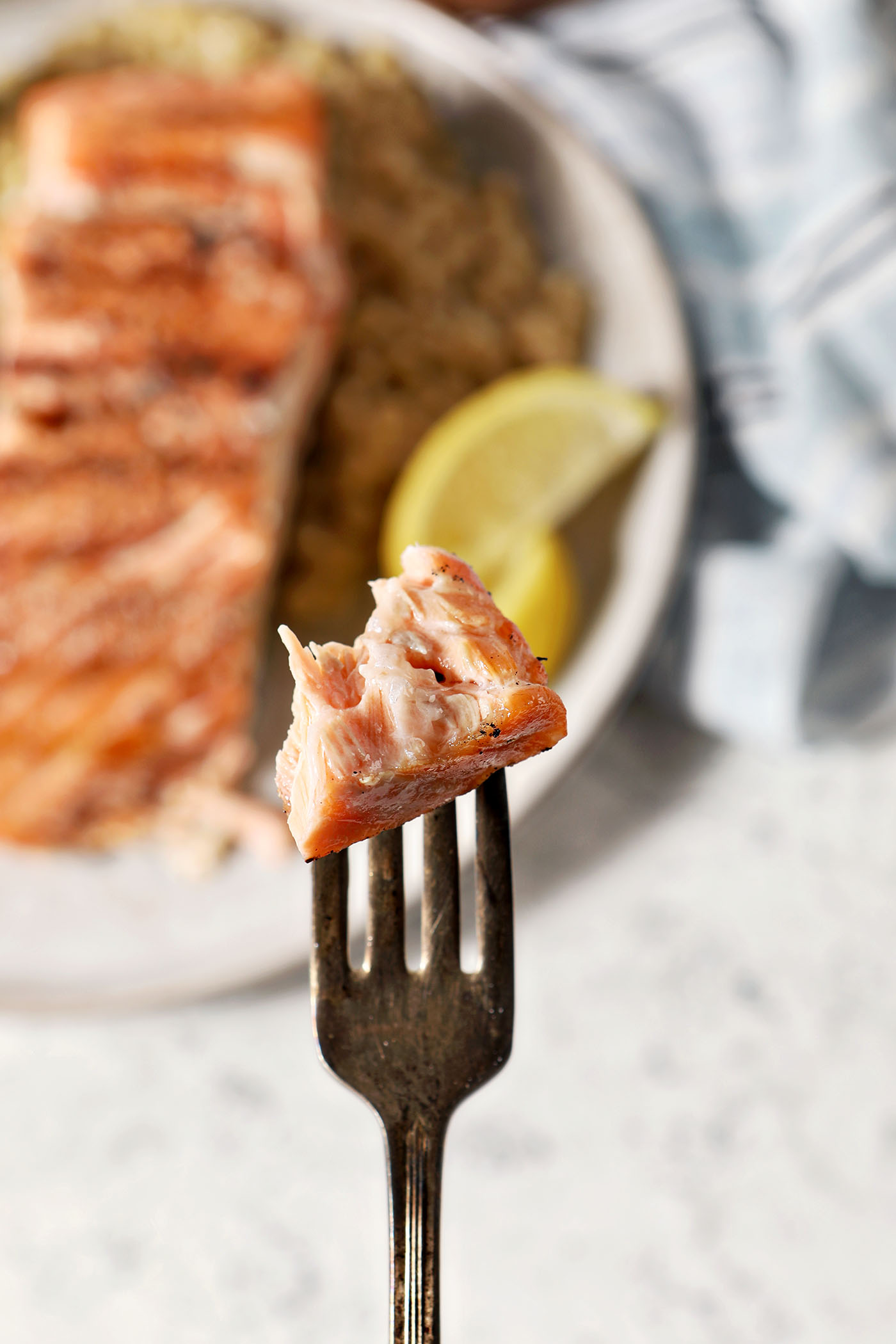 A bite of salmon on a fork above a plate