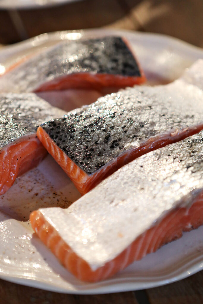 Salmon, flesh side down, on a plate, before cooking