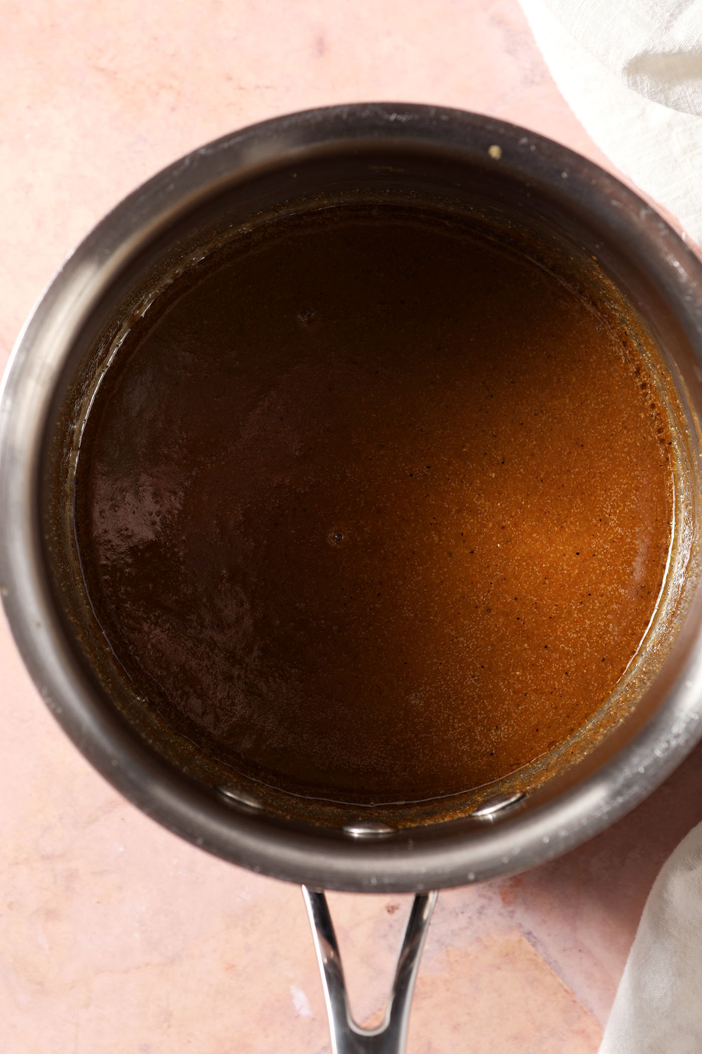 Melted Cajun spice seasoning mixture in a saucepan on a brick surface