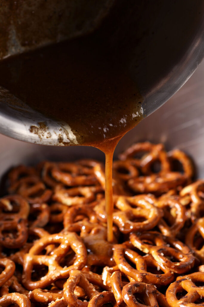 Cajun spice seasoning pours on top of crunchy pretzels in a bowl