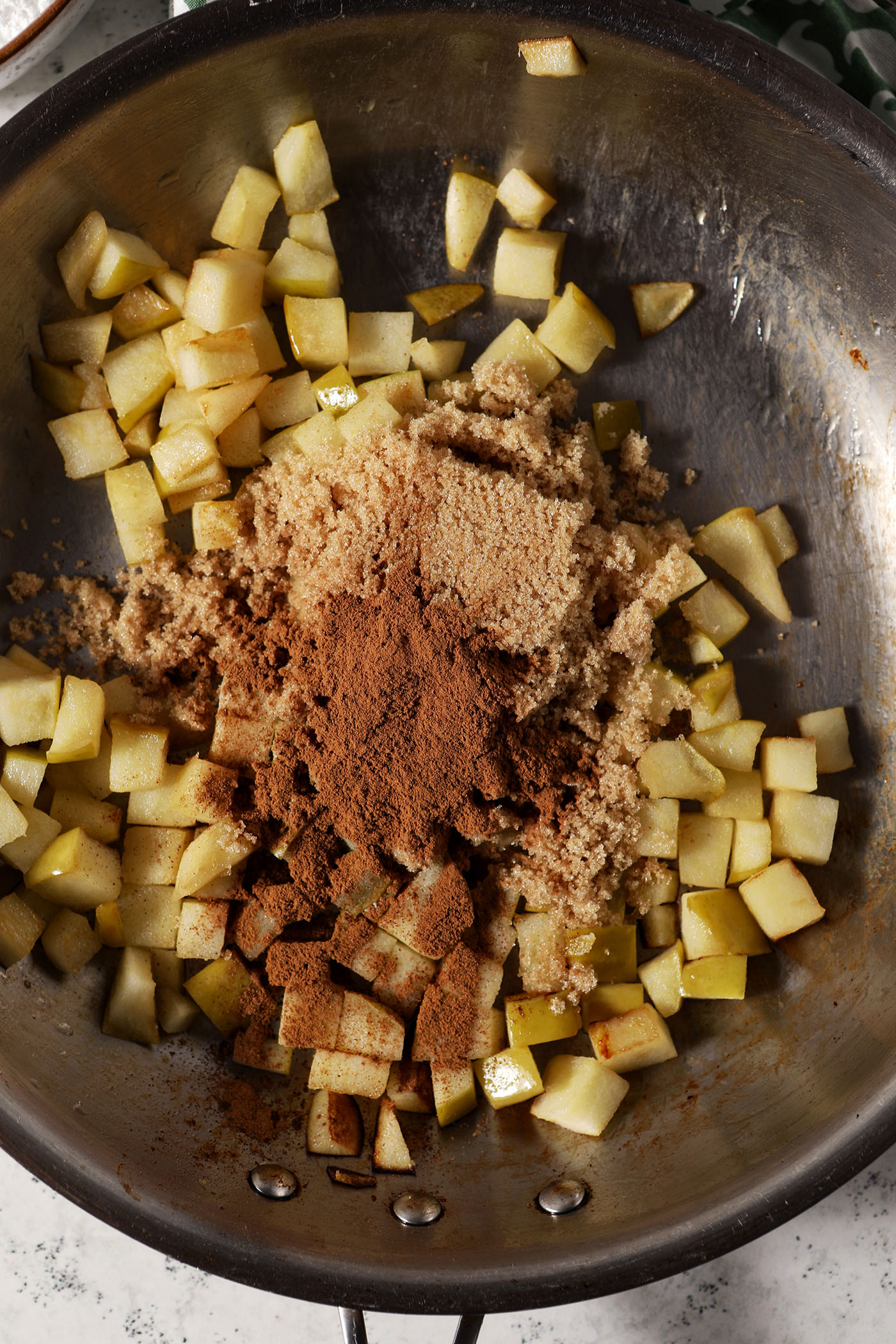 Seasonings on top of diced apples in a skillet