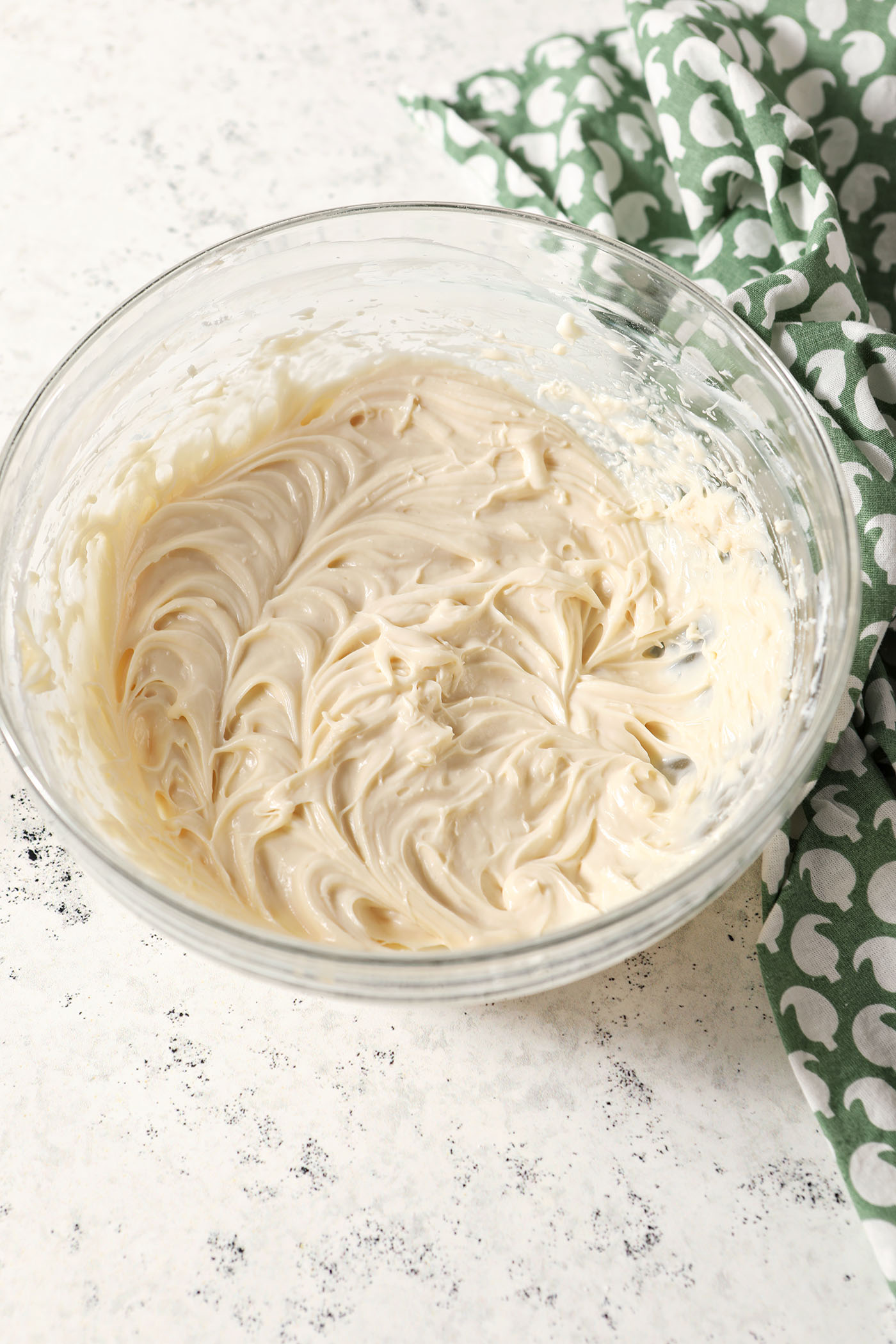 Whipped cheesecake dip in a bowl on a stone surface next to a green patterned linen