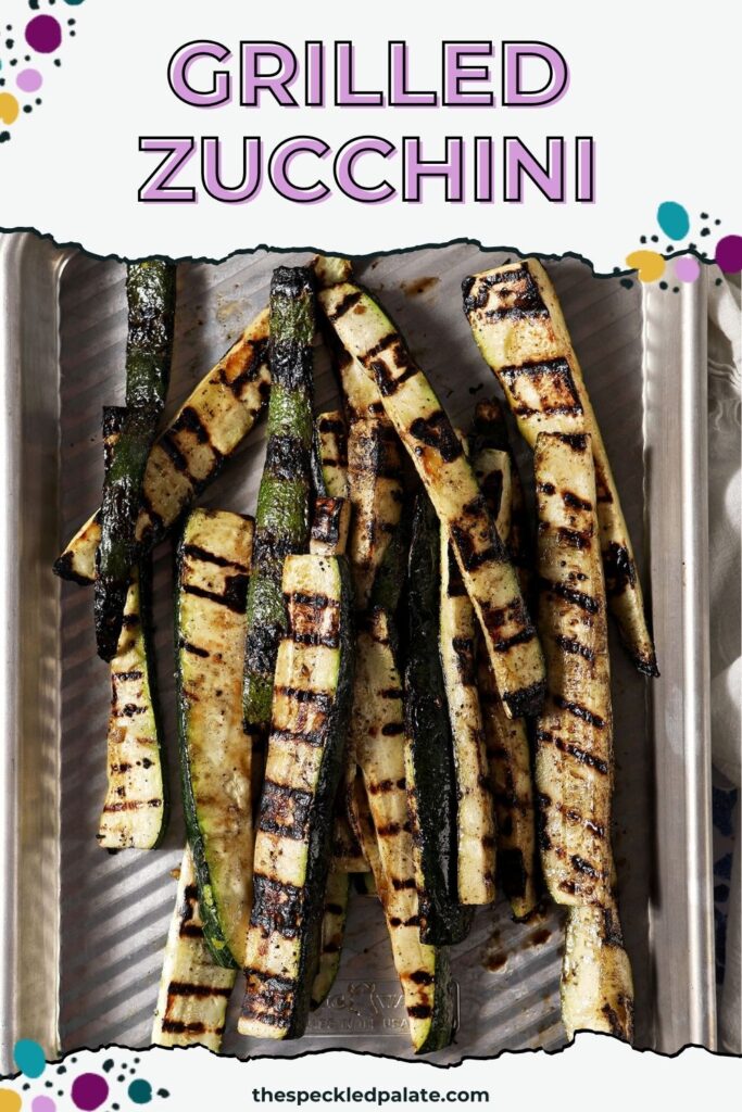 Grilled zucchini slices garnished with grated Parmesan and parsley on a silver sheet pan.