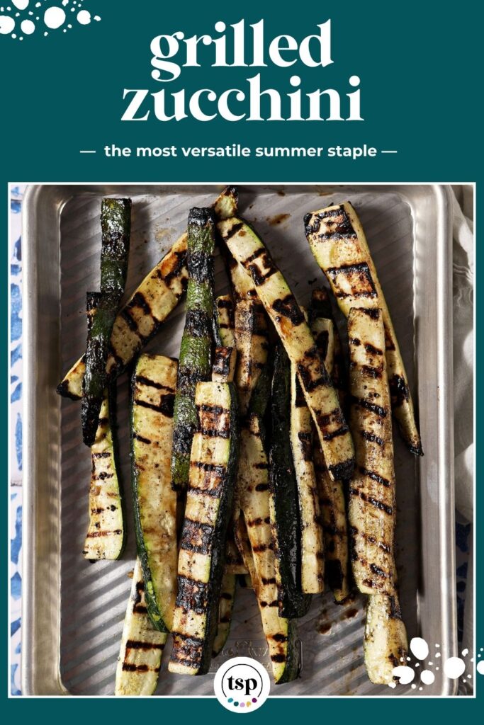 Grilled zucchini slices garnished with grated Parmesan and parsley on a silver sheet pan with the text "Grilled Zuchinni: the most versatile summer staple."