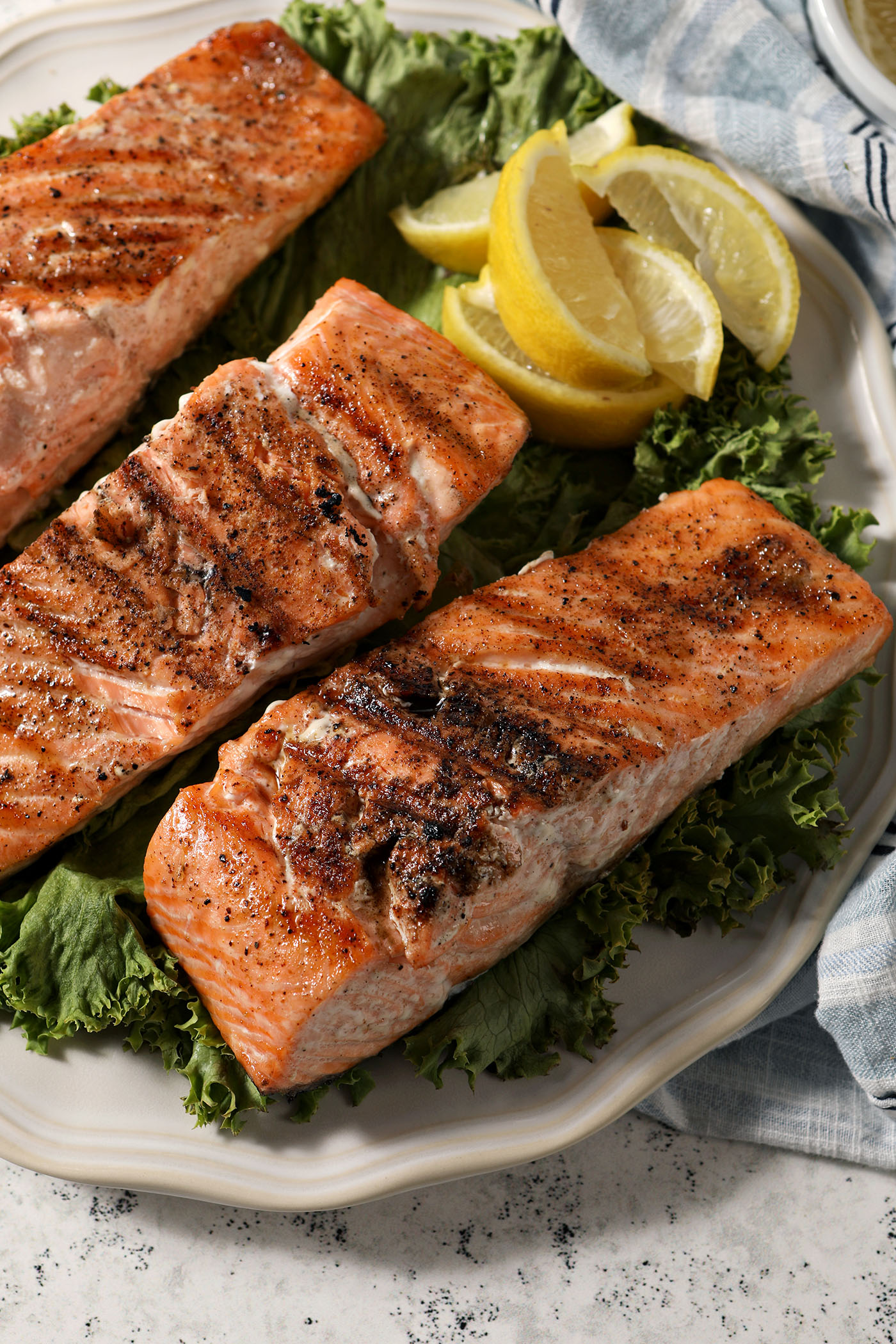 side angle of three filets of salmon on a platter with lemon wedges