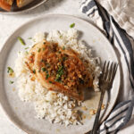 Lemon Garlic Chicken on a plate over rice with a plate of garlic bread and a lemon